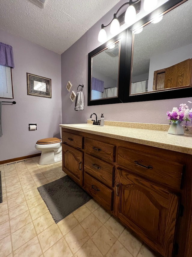 bathroom with vanity, toilet, and a textured ceiling