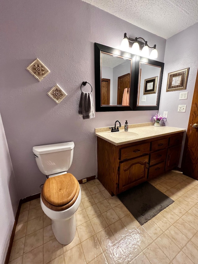 bathroom featuring tile patterned floors, vanity, a textured ceiling, and toilet