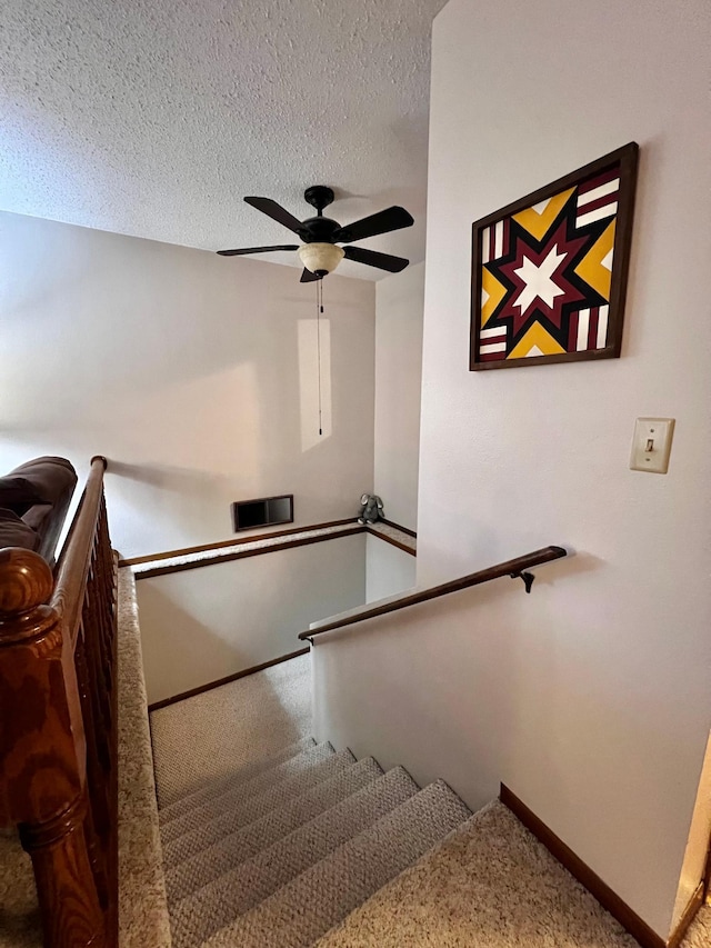 stairs featuring a textured ceiling and ceiling fan