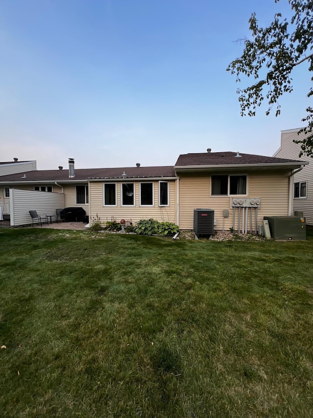 rear view of property with a lawn, a patio area, and central AC