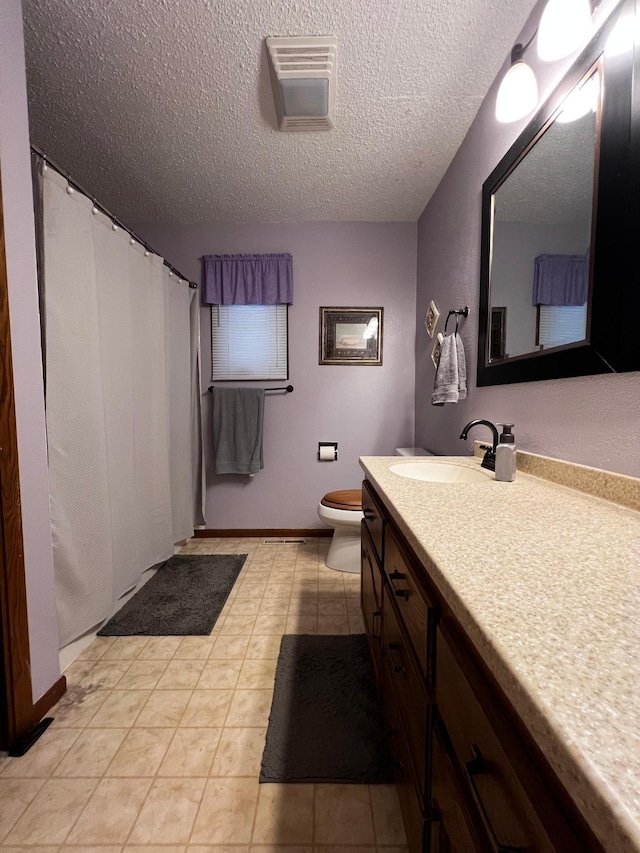 bathroom with tile patterned floors, vanity, a textured ceiling, and toilet