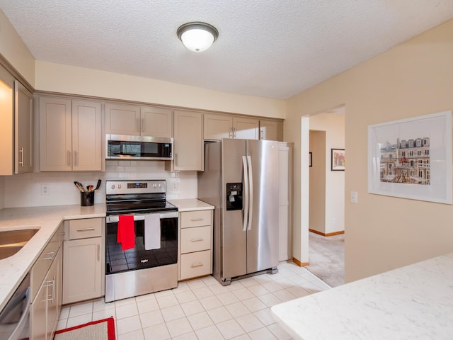 kitchen featuring tasteful backsplash, appliances with stainless steel finishes, gray cabinetry, and a textured ceiling