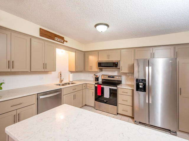 kitchen featuring light tile patterned floors, gray cabinets, appliances with stainless steel finishes, and a sink