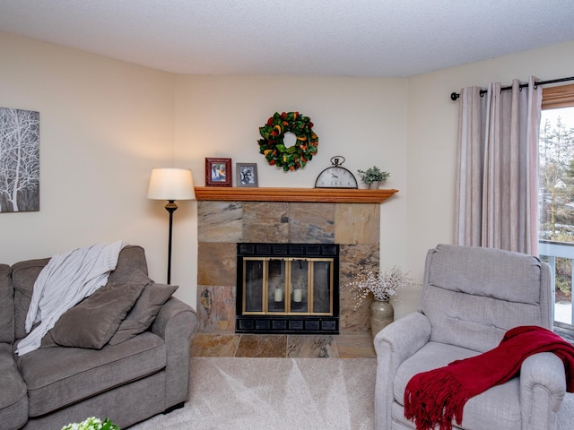 carpeted living room featuring a stone fireplace and a textured ceiling