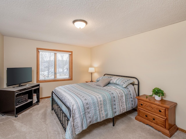 bedroom with baseboards, light carpet, and a textured ceiling