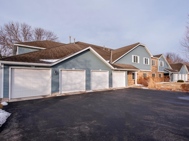 view of front facade with aphalt driveway, an attached garage, and a shingled roof