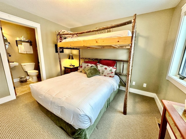 carpeted bedroom with connected bathroom and baseboards