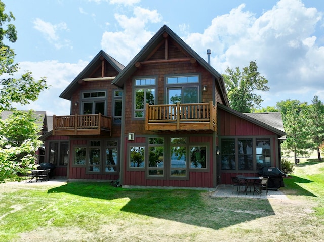 back of house featuring a balcony, board and batten siding, a patio area, and a lawn