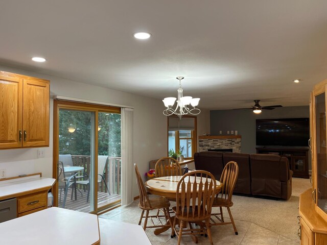 dining room with ceiling fan with notable chandelier, light tile patterned floors, and a fireplace