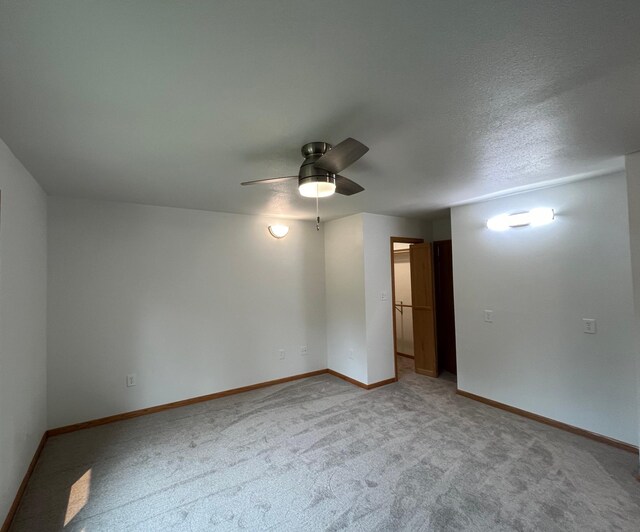 unfurnished room with ceiling fan, a textured ceiling, and carpet flooring