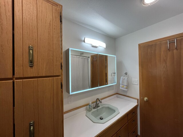 bathroom with walk in shower, vanity, and a textured ceiling