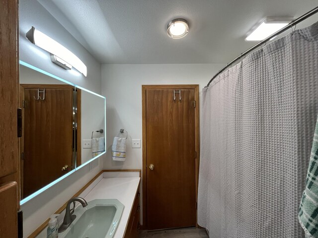 bathroom with walk in shower, vanity, and a textured ceiling