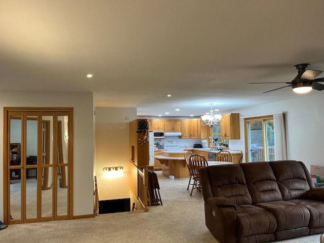 carpeted living room featuring ceiling fan with notable chandelier