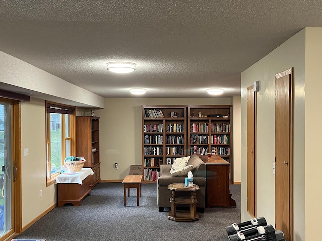 living area featuring dark carpet and a textured ceiling