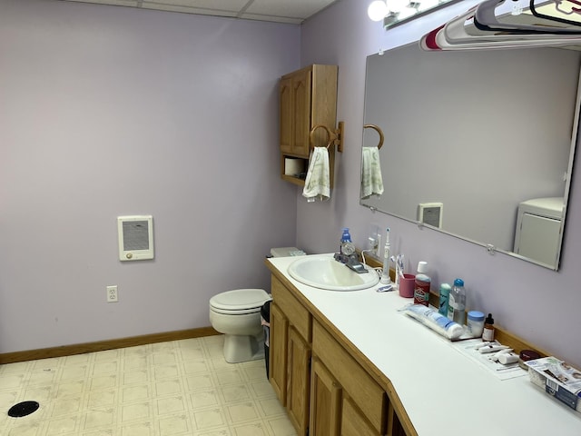 bathroom with heating unit, a paneled ceiling, vanity, and toilet