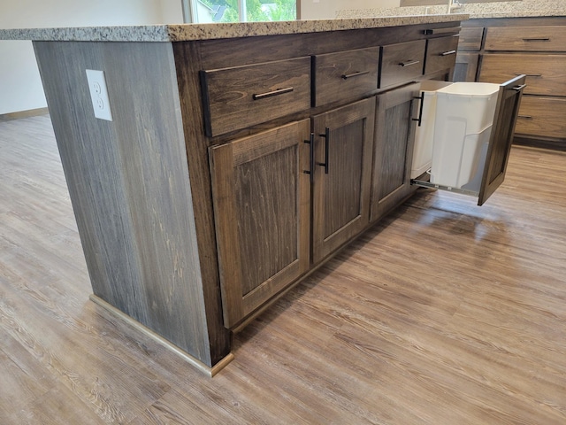 interior details with light stone countertops, dark brown cabinetry, and light hardwood / wood-style floors