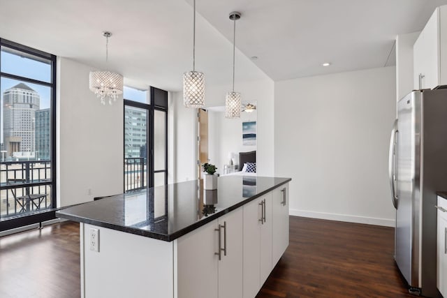 kitchen with a wealth of natural light, white cabinetry, freestanding refrigerator, and dark wood-type flooring