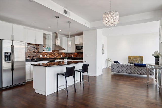 kitchen featuring visible vents, dark wood finished floors, stainless steel appliances, dark countertops, and wall chimney exhaust hood