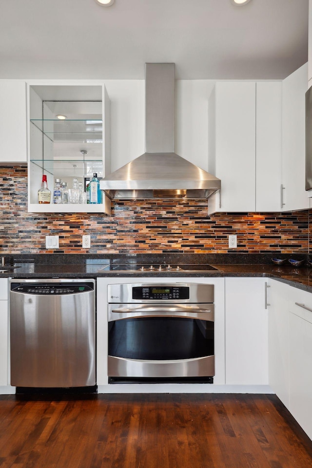 kitchen with backsplash, white cabinets, stainless steel appliances, and wall chimney range hood