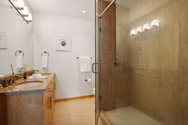 bathroom featuring a sink, baseboards, double vanity, and a shower stall