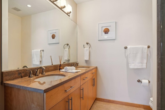 bathroom featuring double vanity, toilet, visible vents, and a sink