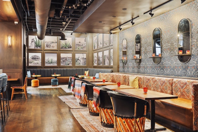 dining space featuring hardwood / wood-style floors, rail lighting, and wallpapered walls