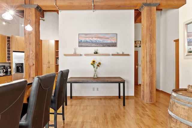 dining room featuring decorative columns, light hardwood / wood-style floors, and beamed ceiling