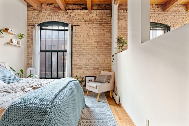 bedroom featuring beam ceiling, multiple windows, and light wood-type flooring