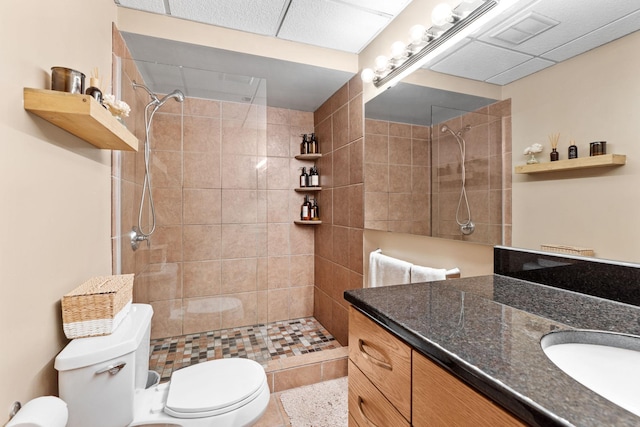 bathroom with vanity, a tile shower, toilet, and tile patterned flooring