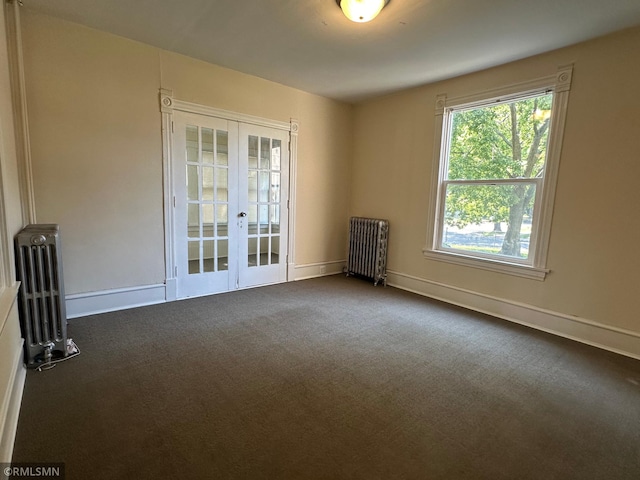 carpeted spare room featuring radiator and french doors