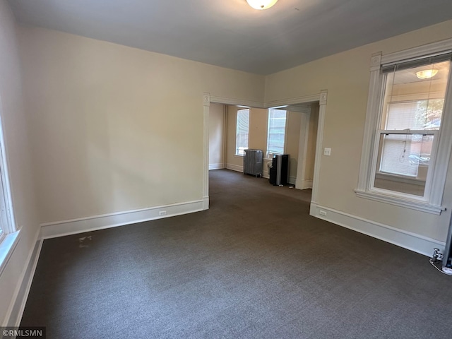 carpeted empty room featuring a wealth of natural light and radiator