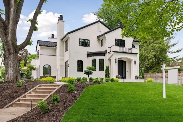 view of front facade with a balcony and a front lawn