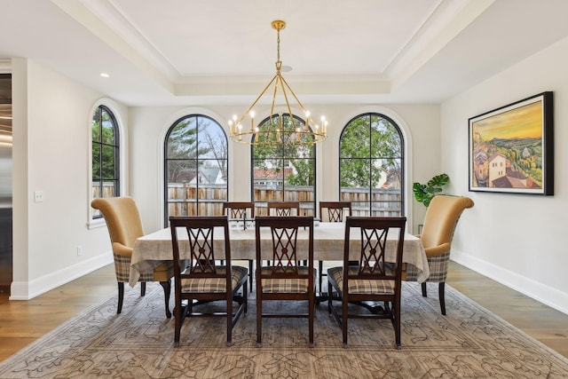 dining room with a notable chandelier, dark hardwood / wood-style flooring, and a tray ceiling