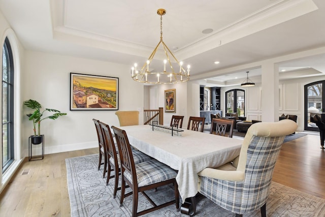 dining area with crown molding, light hardwood / wood-style flooring, and a raised ceiling