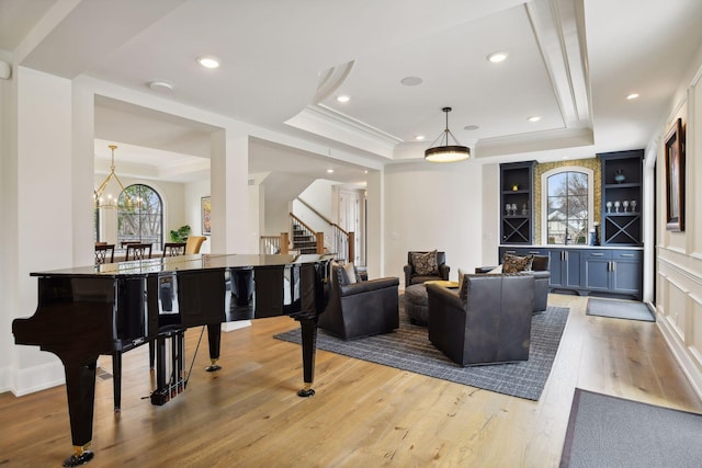 living room featuring crown molding, light hardwood / wood-style flooring, a chandelier, and a tray ceiling