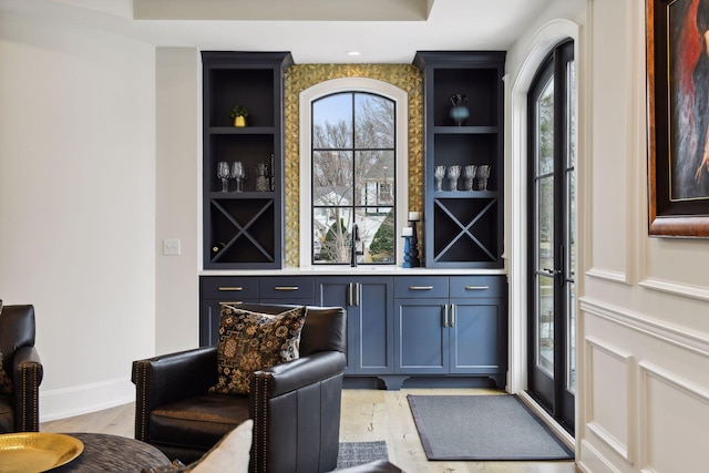 bar with sink, built in features, light hardwood / wood-style floors, and blue cabinetry