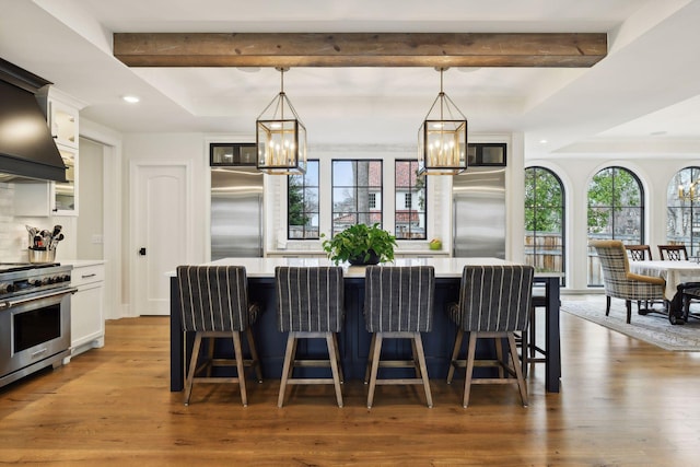 kitchen with high end appliances, white cabinetry, a kitchen island, and pendant lighting