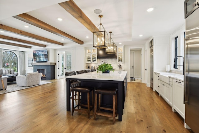 kitchen with hardwood / wood-style floors, pendant lighting, white cabinetry, a kitchen breakfast bar, and a center island