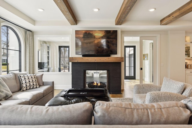 living room featuring a multi sided fireplace, beam ceiling, and light hardwood / wood-style floors