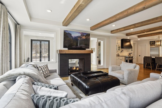 living room featuring dark wood-type flooring, a multi sided fireplace, an inviting chandelier, and beamed ceiling