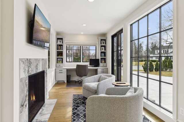 home office featuring built in desk, light hardwood / wood-style floors, and a premium fireplace