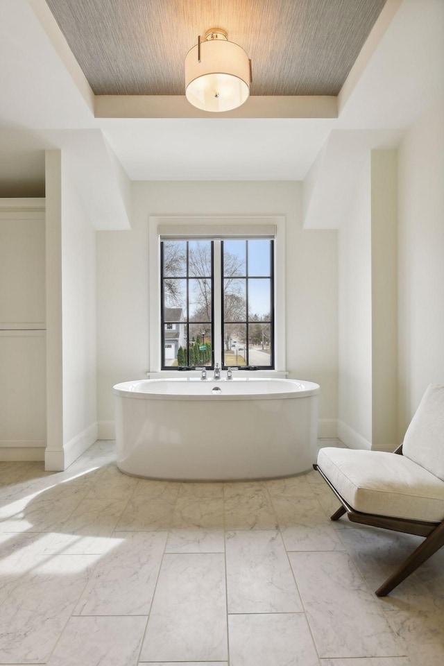 bathroom with a raised ceiling, a bathtub, and wooden ceiling