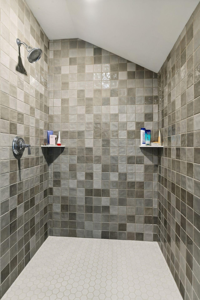 bathroom featuring lofted ceiling and a tile shower