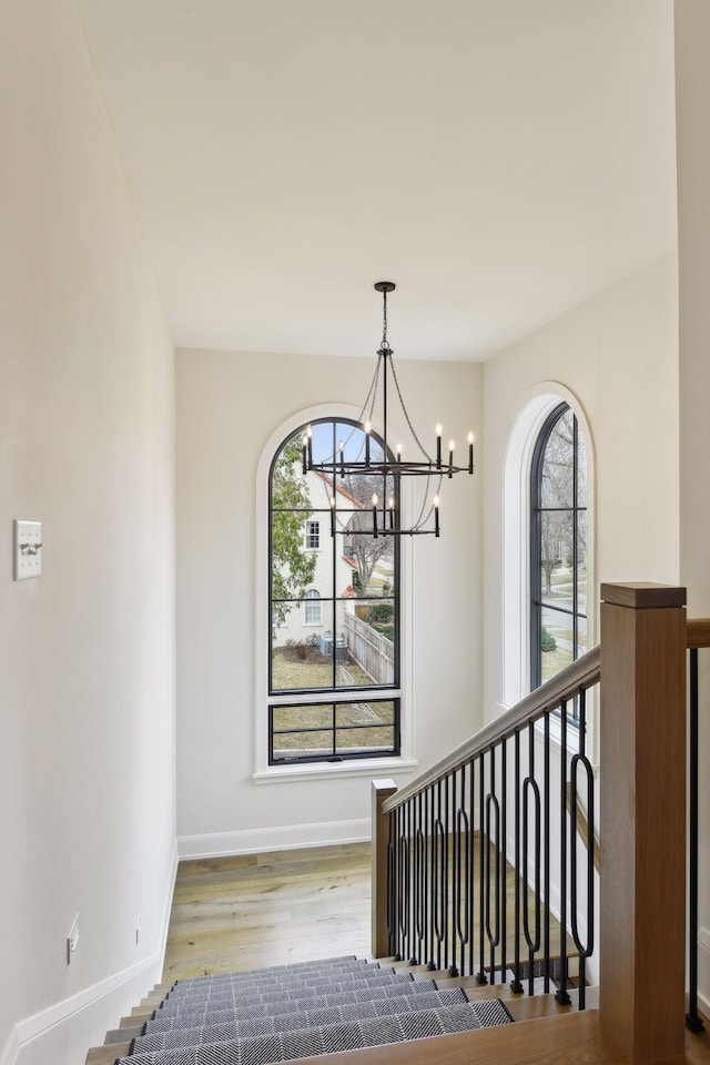 stairs with hardwood / wood-style flooring, a healthy amount of sunlight, and a notable chandelier