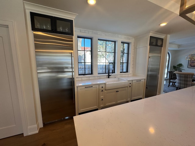 kitchen with dark wood-type flooring, sink, white cabinetry, ornamental molding, and appliances with stainless steel finishes