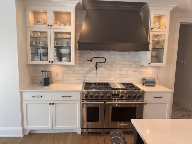 kitchen with white cabinetry, double oven range, tasteful backsplash, and wall chimney exhaust hood