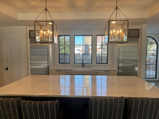 kitchen featuring decorative light fixtures, high end fridge, stainless steel refrigerator, and a tray ceiling