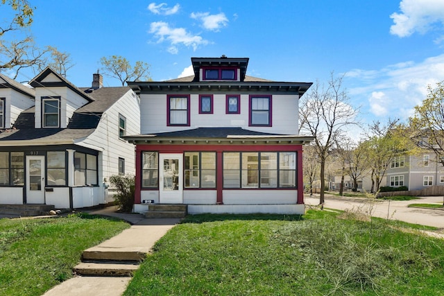 view of front of property with entry steps, a sunroom, and a front yard