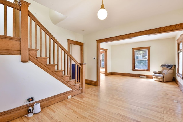 entryway with baseboards, stairs, and light wood-style flooring