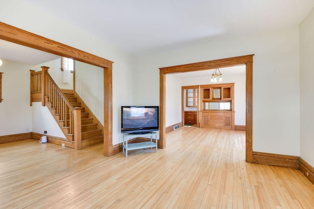 living room featuring hardwood / wood-style flooring, baseboards, and stairs